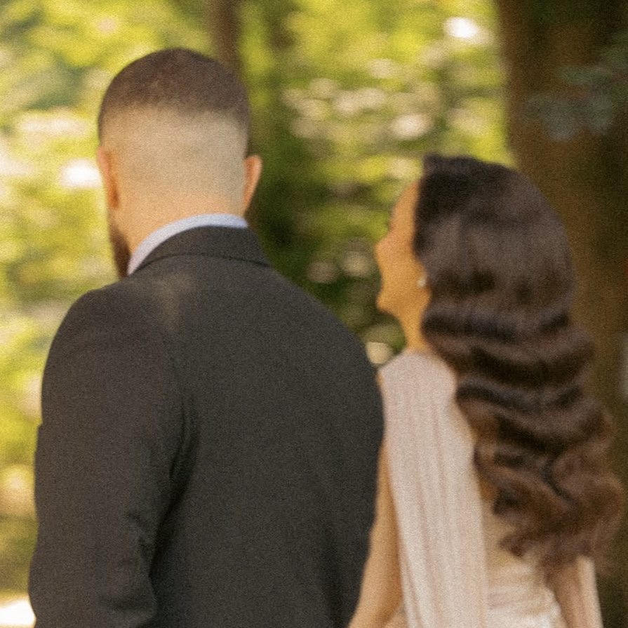 Rückansichten eines Paares in Hochzeitskleidung, verschwommener Waldhintergrund